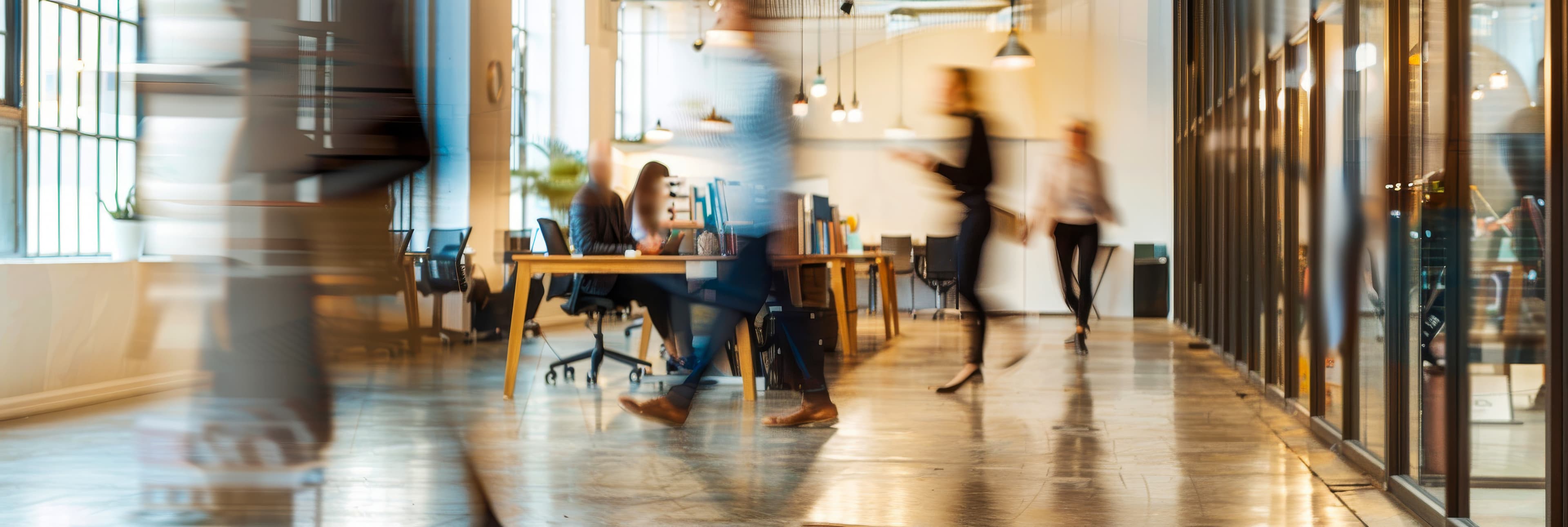 People moving and working throughout a contemporary open-plan workplace.